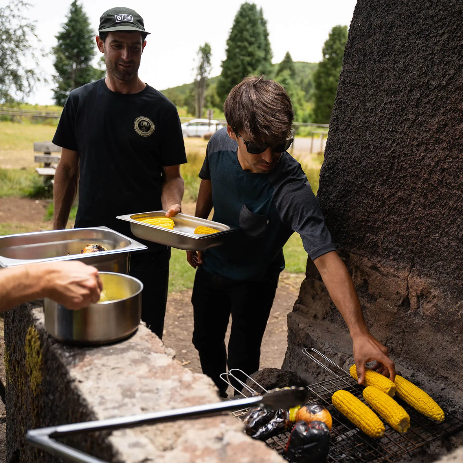 People preparing food at an outdoor barbecue, part of a mountain bike event, emphasizing mountain bike content creation and marketing strategies. LOAM.