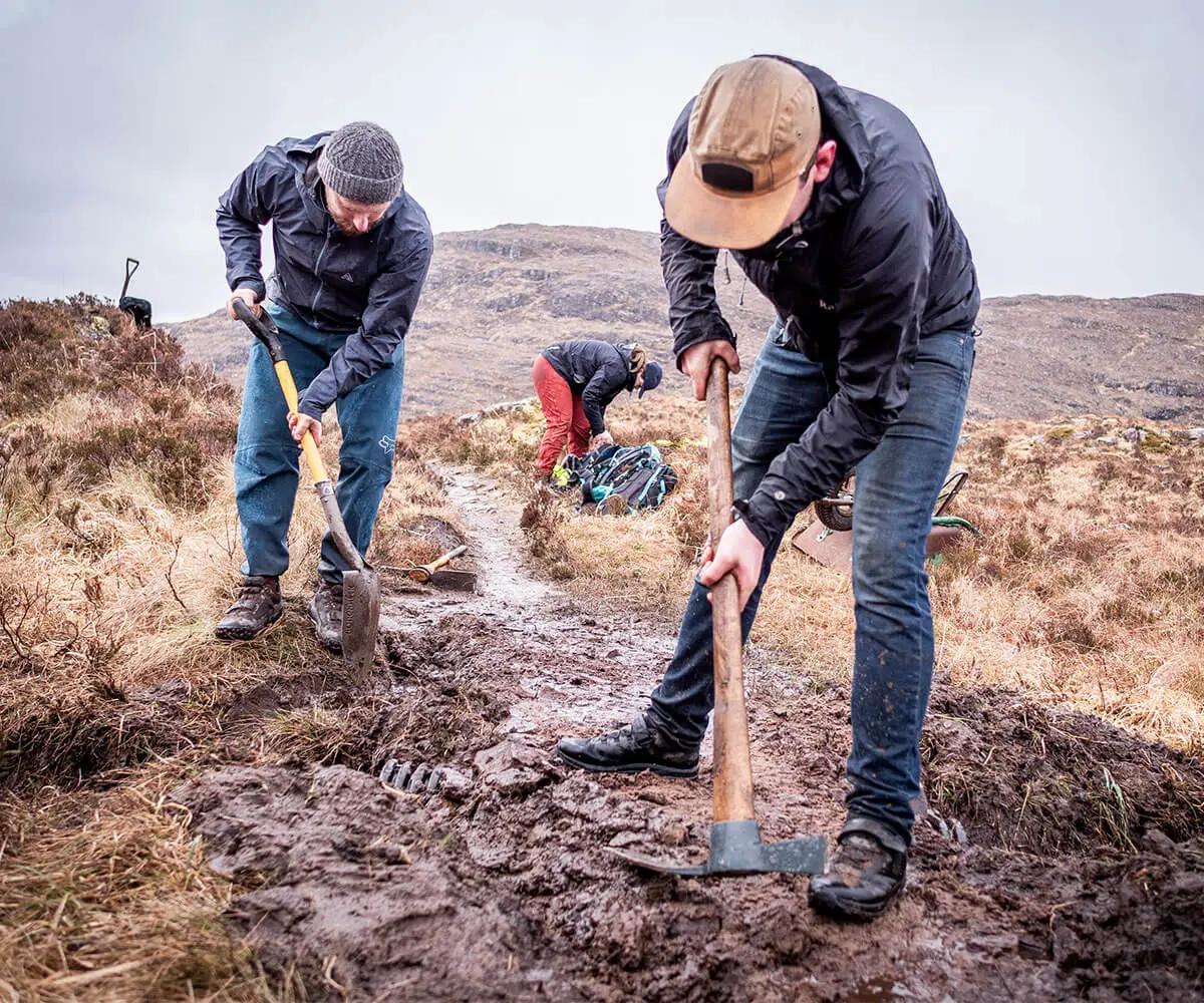 LOAM x H+I Adventures Applecross Trail Maintenance crew working on muddy path, showcasing mountain bike marketing agency projects in rugged terrain. LOAM.