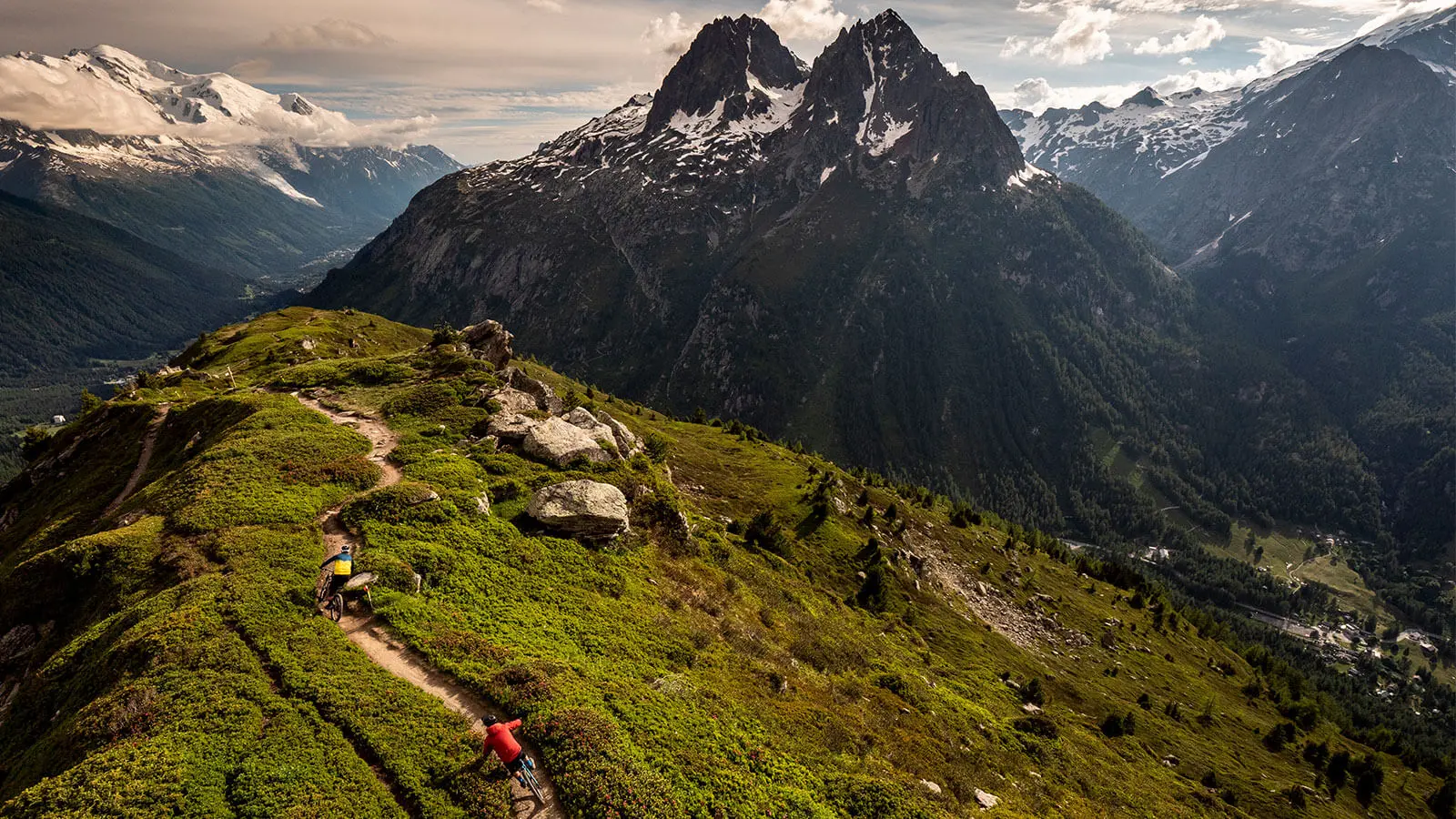 Mountain bikers on a trail with scenic mountains; ideal for Mountain Bike Marketing Agency, Content Creation, and Event Planning. LOAM.