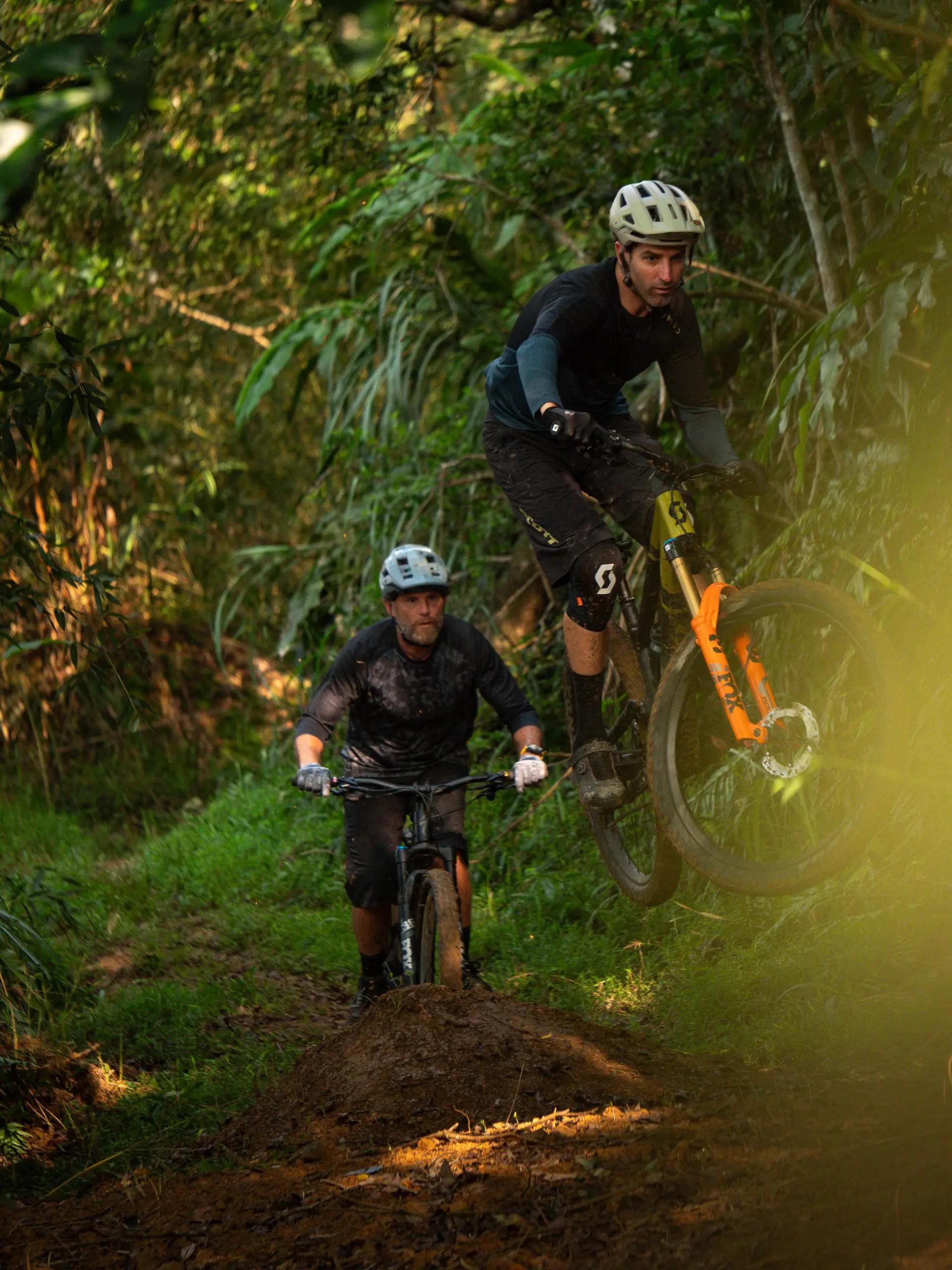 Mountain bikers in action on a forest trail, ideal for mountain bike content creation and marketing agency promotion. LOAM.