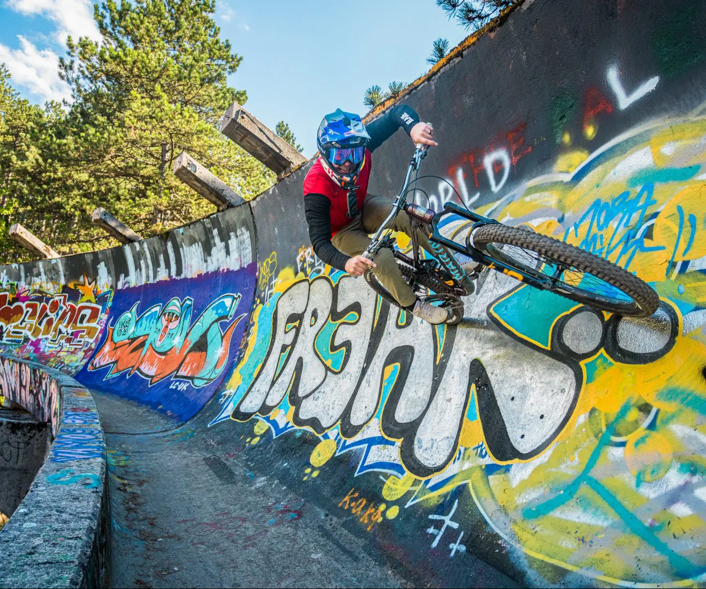 Mountain biker tackles graffiti-covered wall, showcasing skills for Mountain Bike Ambassador Management and Mountain Bike Content Creation. LOAM.