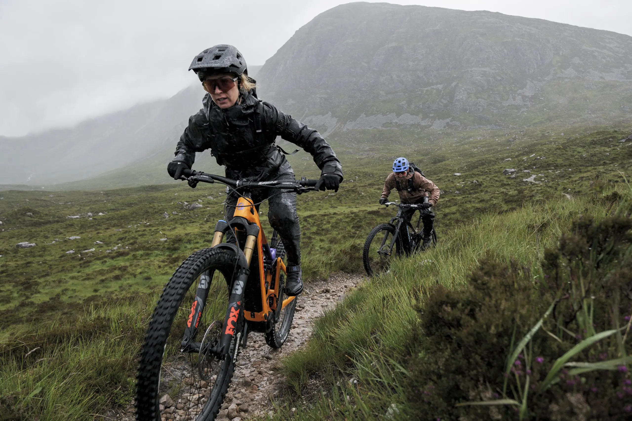 Mountain bikers navigate rugged trail in scenic landscape, showcasing Around the World With LOAM and Euan Wilson’s Global Trail Adventures. LOAM.