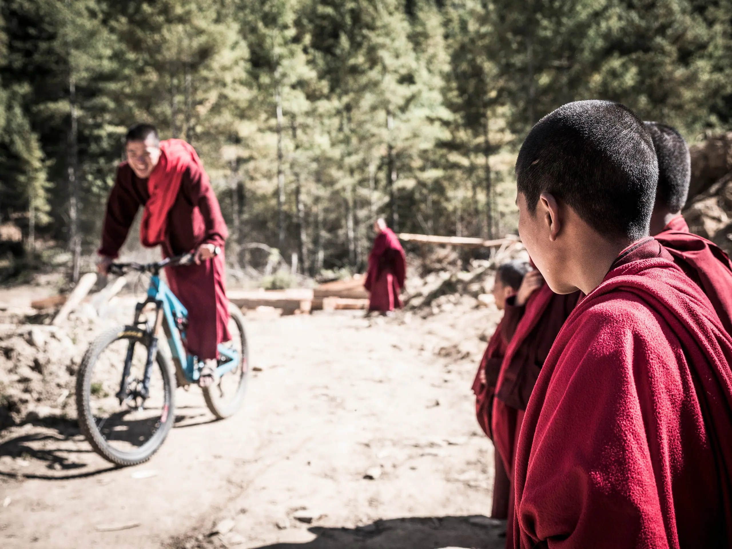Mountain bikers in red robes on a trail, showcasing Euan Wilson’s Global Trail Adventures. Mountain Bike Content Creation for Around the World With LOAM. LOAM.