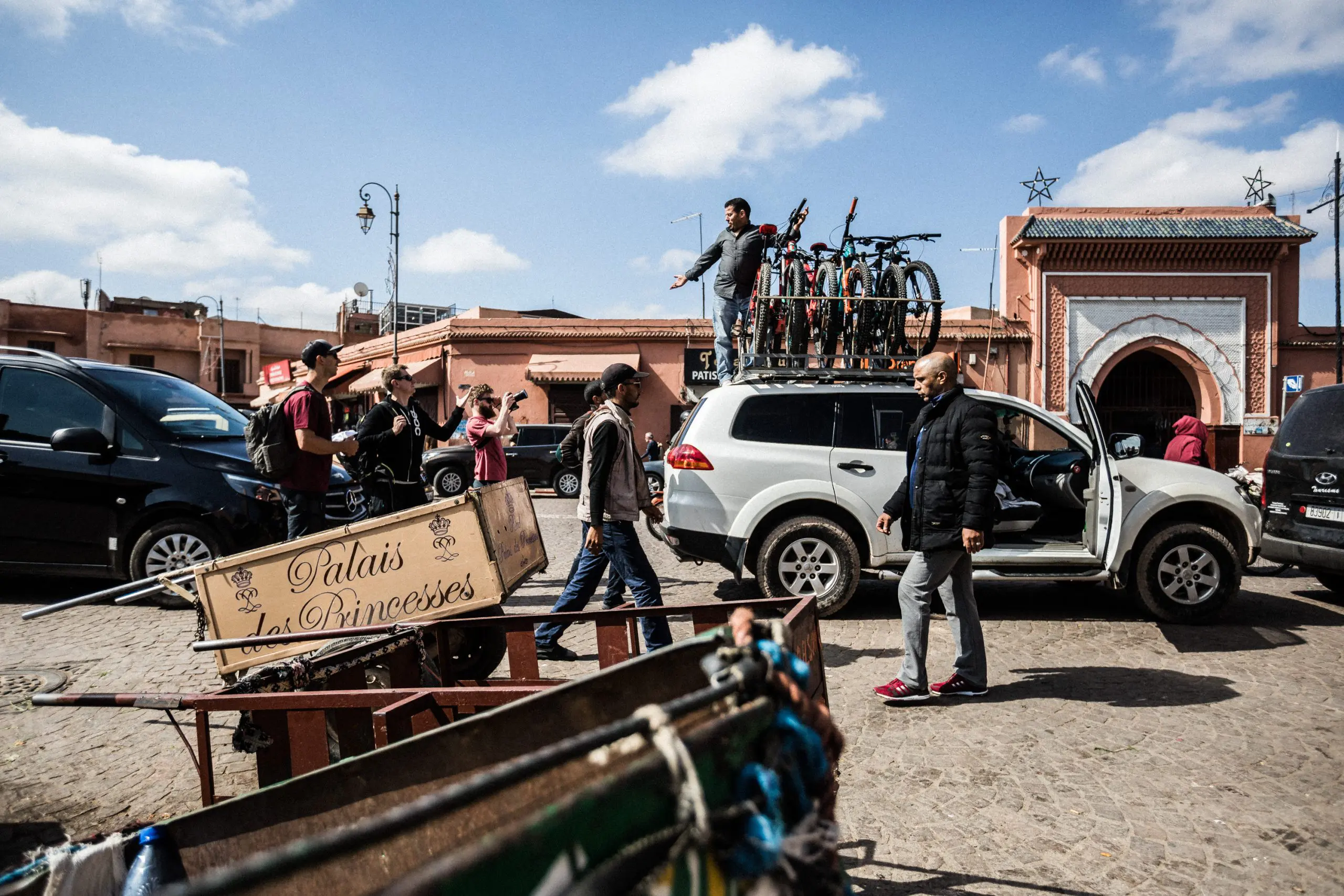 Euan Wilson's Global Trail Adventures with LOAM's mountain bikes loaded on a car in a bustling street scene, showcasing international mountain bike logistics. LOAM.