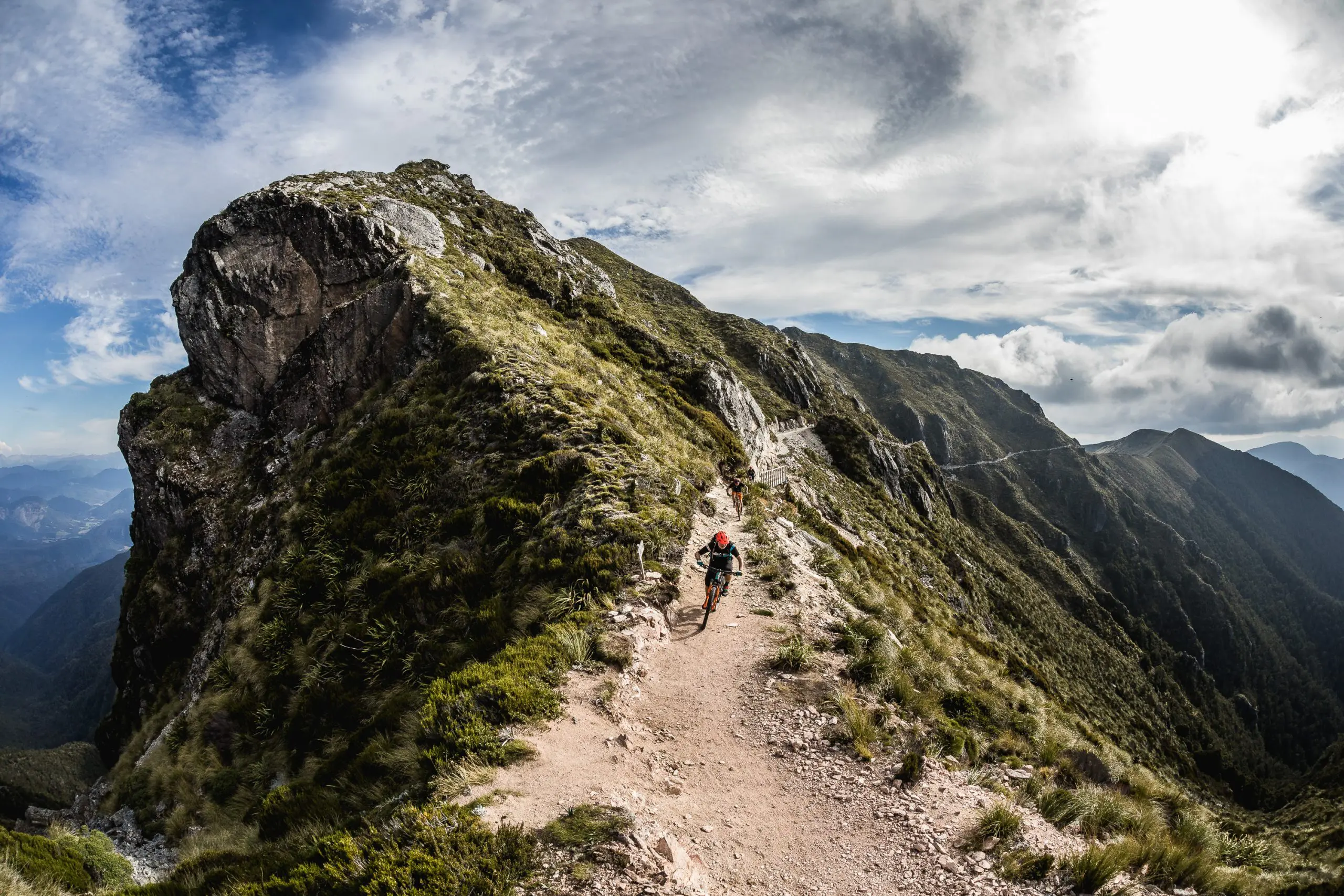 Mountain biker on rocky trail with scenic views, part of Euan Wilson's Global Trail Adventures in 