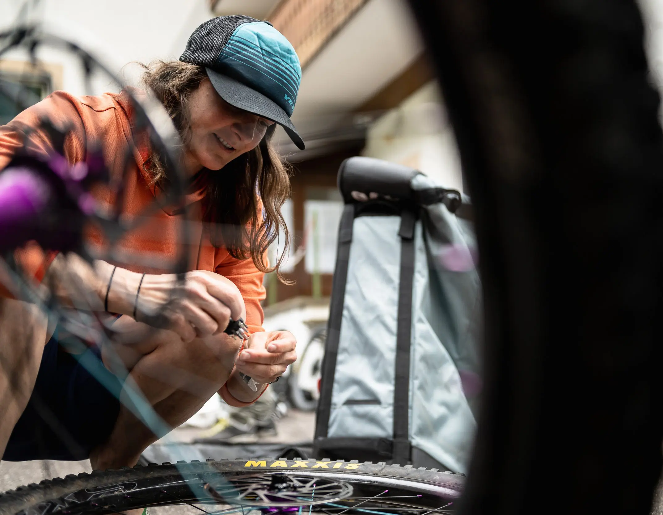 Person fixing a mountain bike wheel, illustrating Mountain Bike Project Logistical Support. Fits Outdoor Sports Project needs and content creation. LOAM.