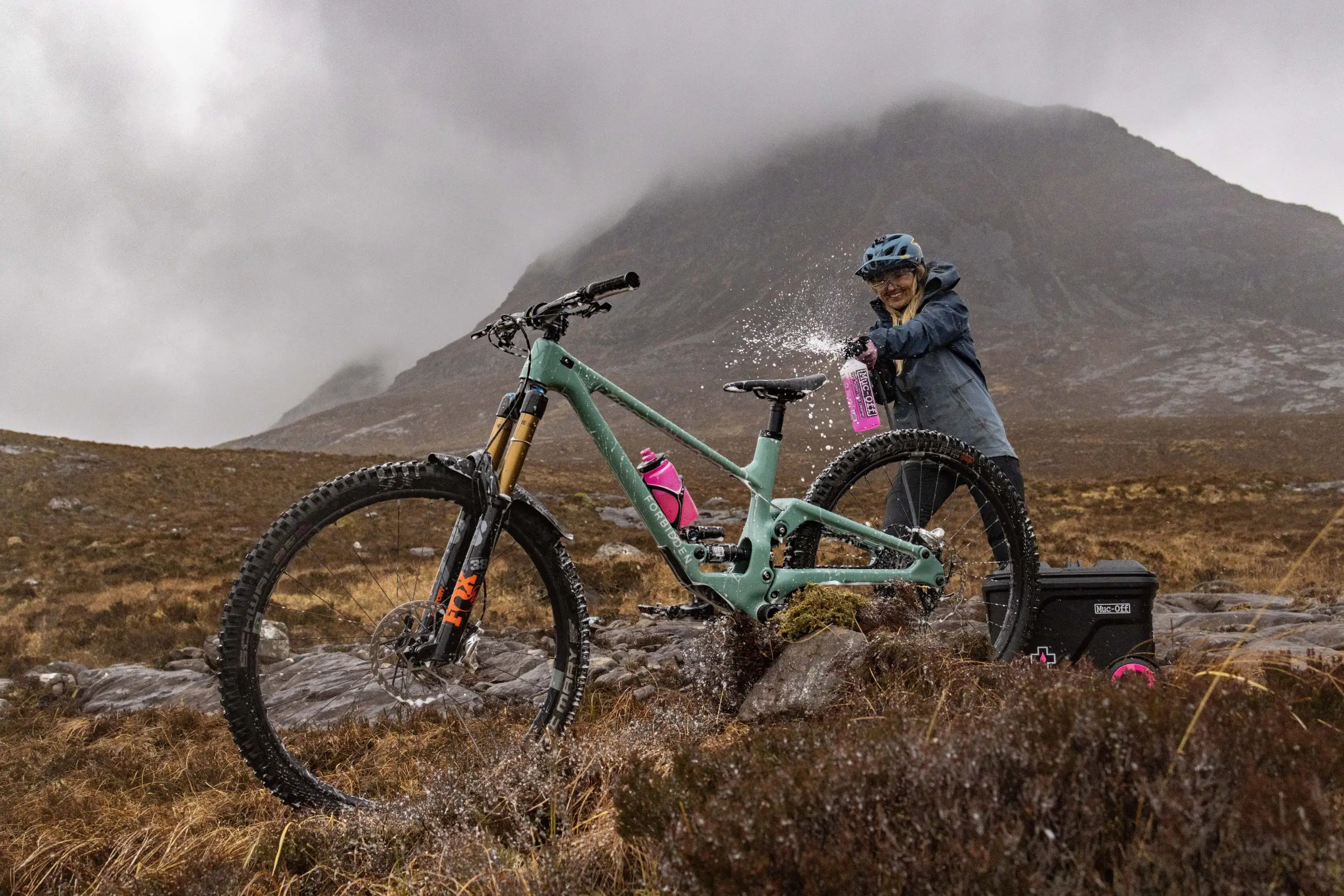 Mountain biker using Muc-Off Mobile Pressure Washer for event planning support in rugged terrain. Ideal for marketing and logistical support needs. LOAM.