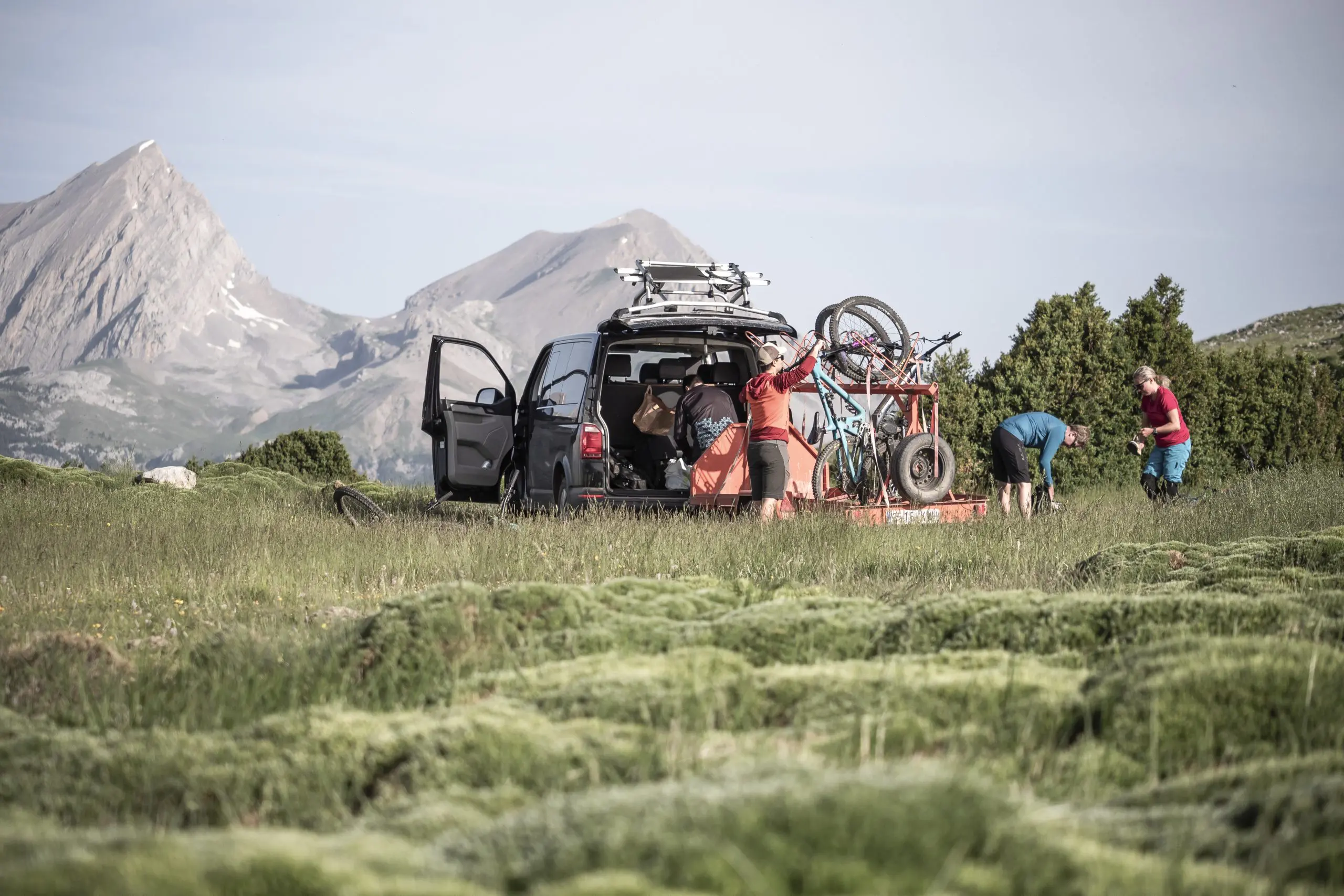 People preparing mountain bikes near a van in scenic mountains, related to Mountain Bike Press Camp, Mountain Bike Event Planner, and Mountain Bike Marketing Agency. LOAM.