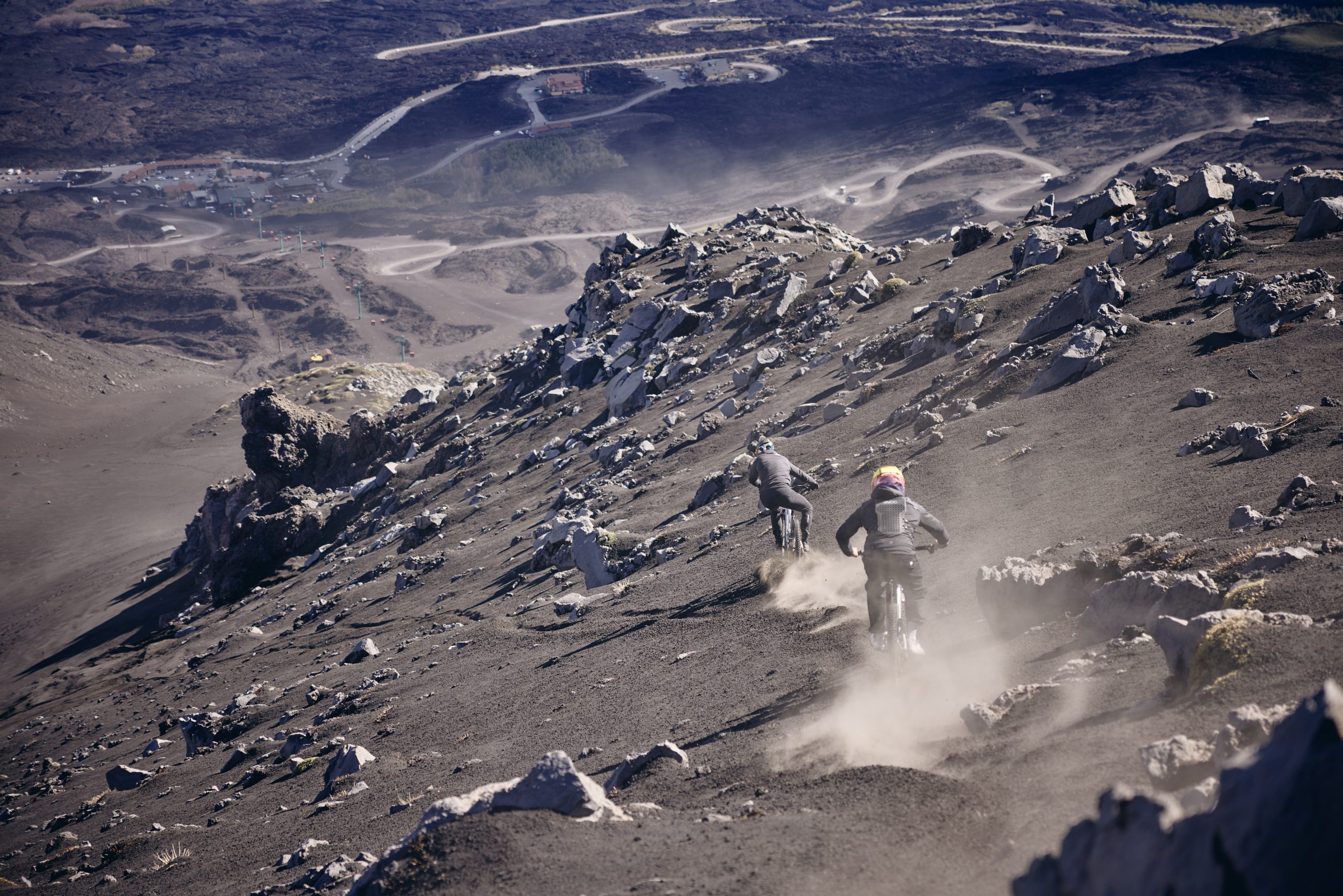 Mountain bikers descending rocky terrain, highlighting Mountain Bike Press Camp planning and content creation, with logistical support for events. LOAM.