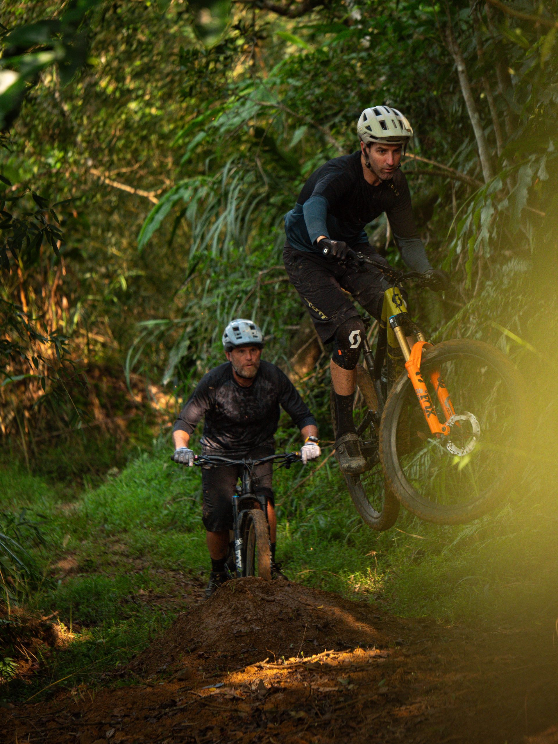Mountain bikers in action on a forest trail, ideal for mountain bike content creation and marketing agency promotion. LOAM.