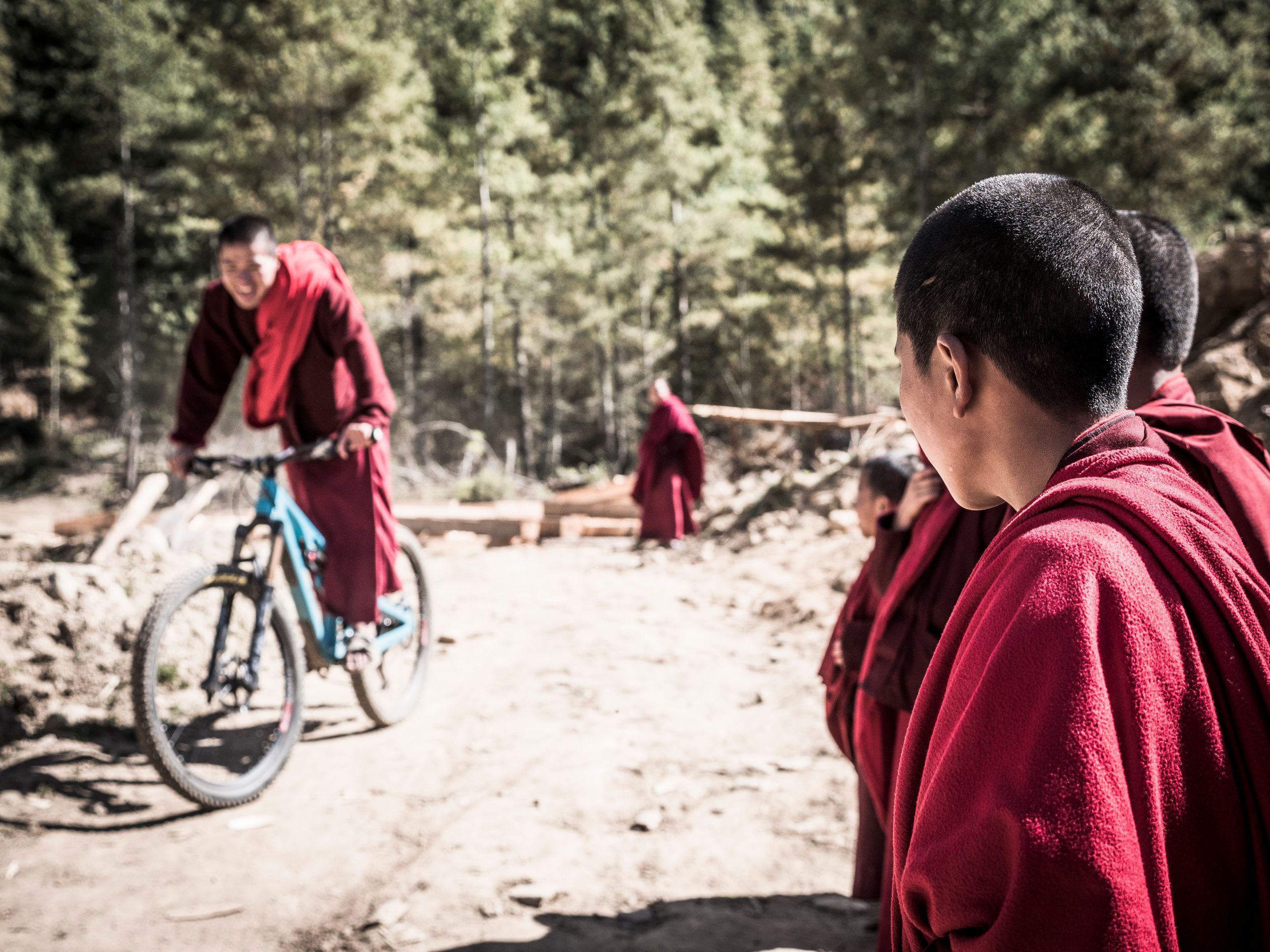 Mountain bikers in red robes on a trail, showcasing Euan Wilson’s Global Trail Adventures. Mountain Bike Content Creation for Around the World With LOAM. LOAM.