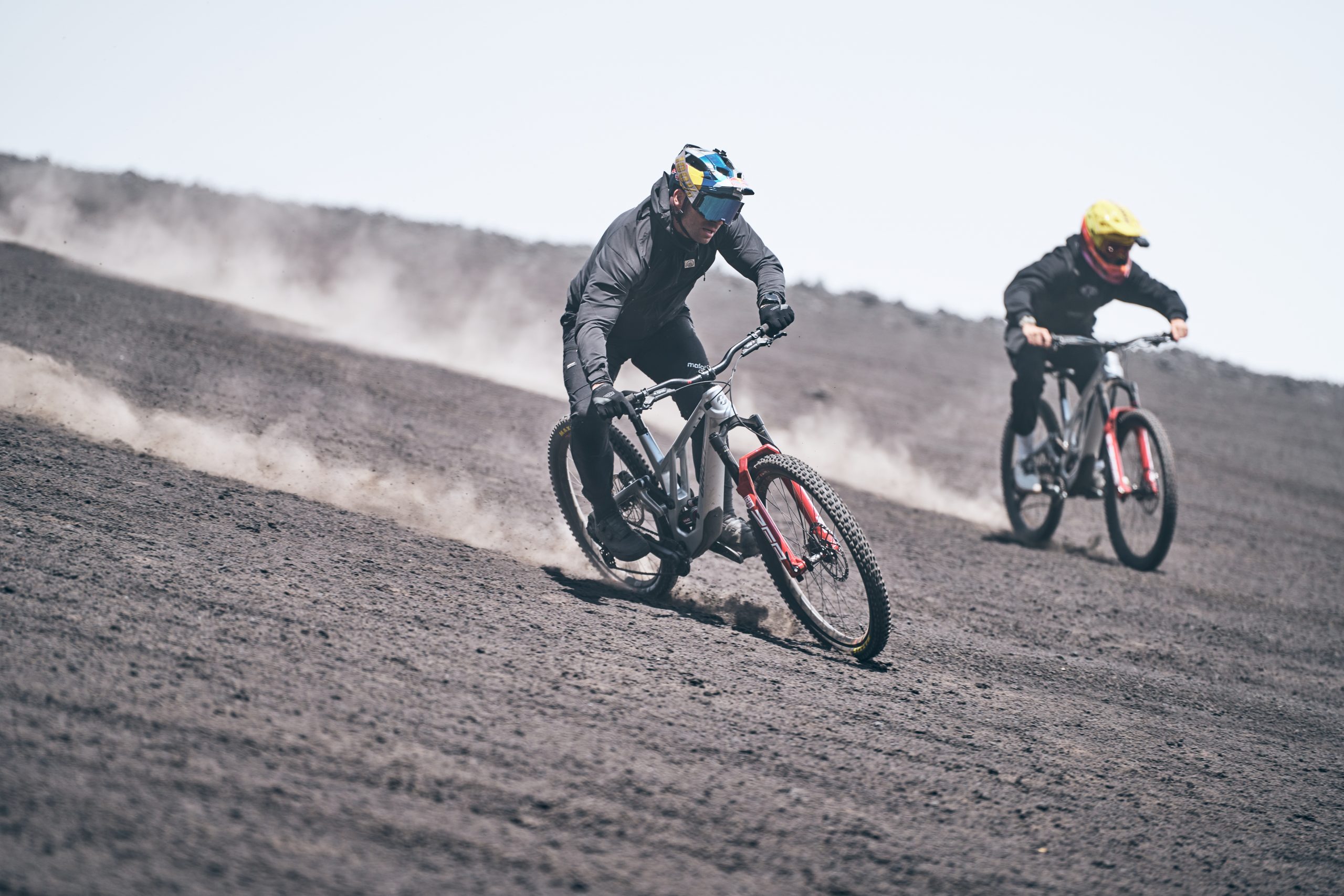 Mountain bikers on a trail, showcasing speed and skill at a Mountain Bike Press Camp. Ideal for Mountain Bike Marketing and Event Planning content. LOAM.